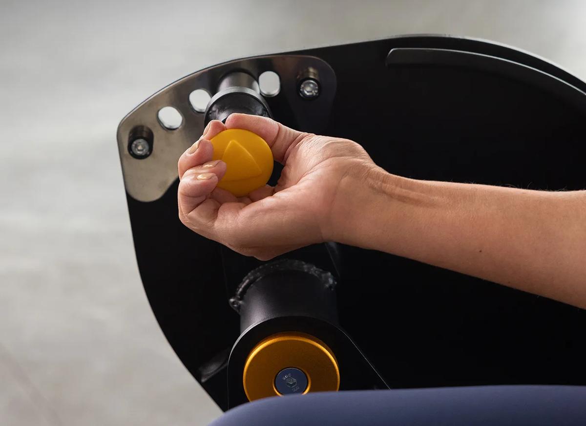 Close-up of a person using the Keystone Leg Extension adjustment arm with yellow pop-pin and pivot hardware.