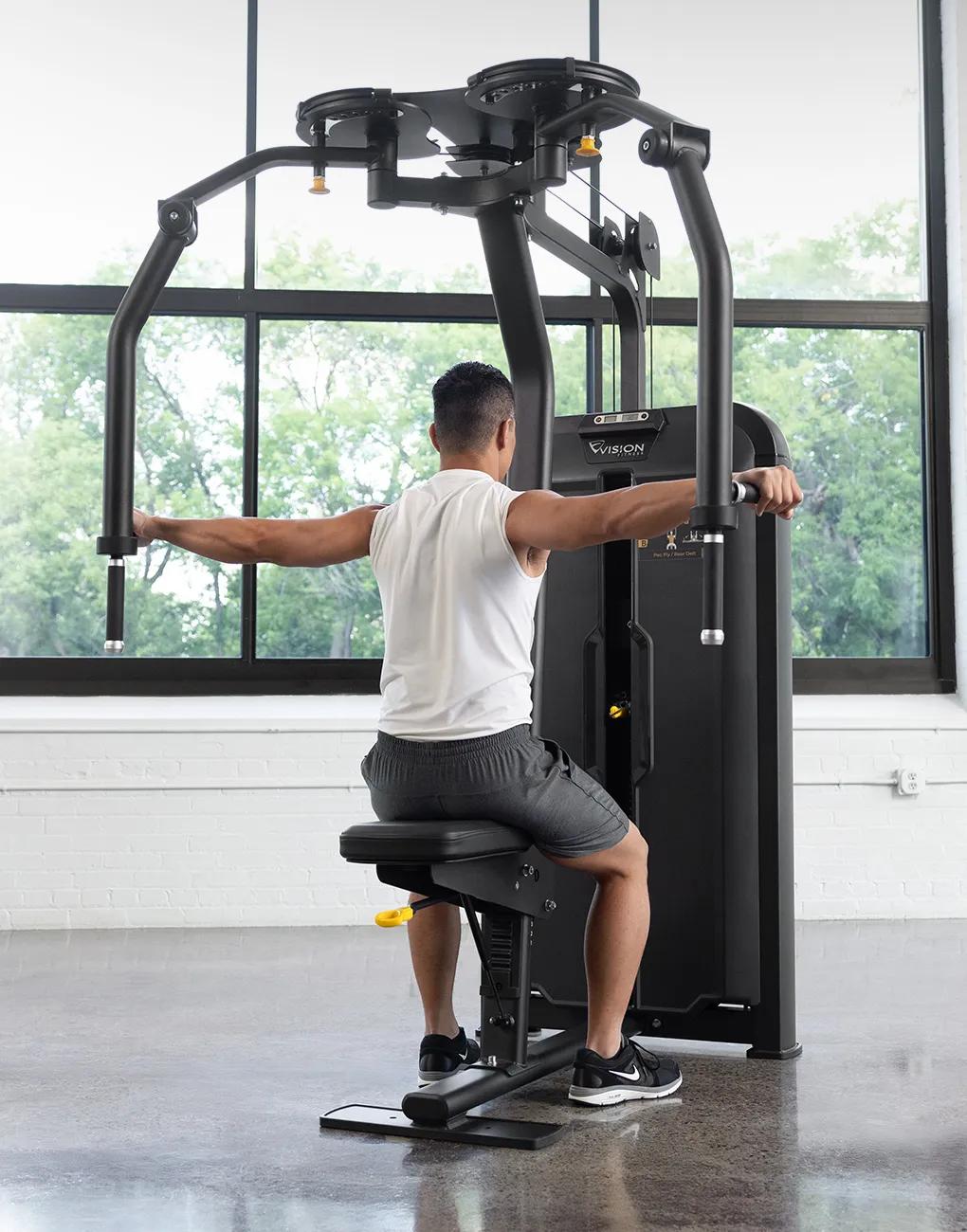 Person using the Vision Fitness Pec Fly/Rear Delt machine to perform a rear delt fly exercise, seated with arms extended outward in a bright gym.