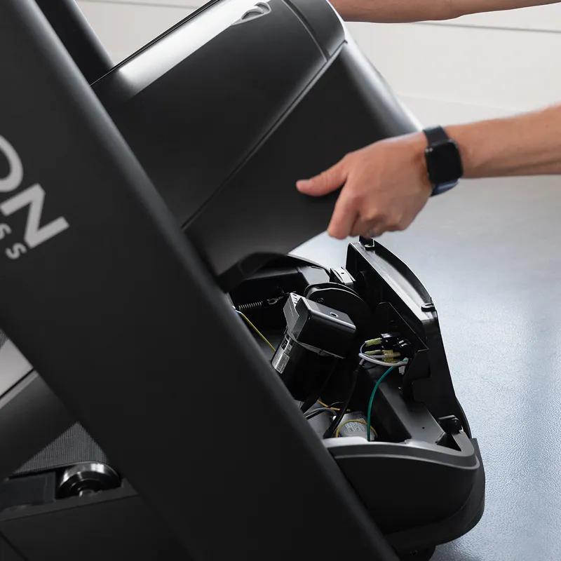 Close-up of a person doing maintenance on the Summit Treadmill with its case opened.