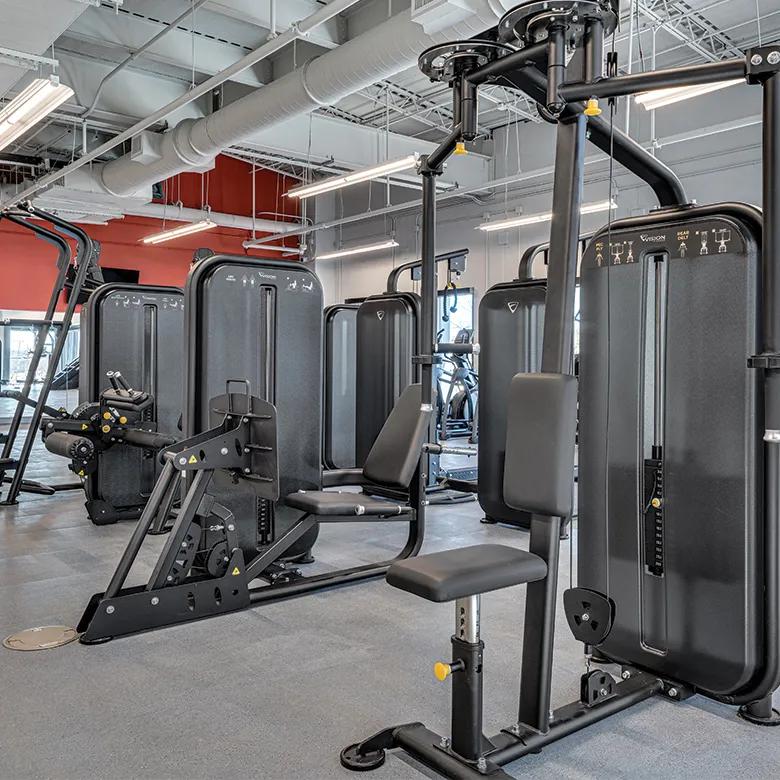 Una línea de aparatos de entrenamiento de fuerza en un gimnasio.