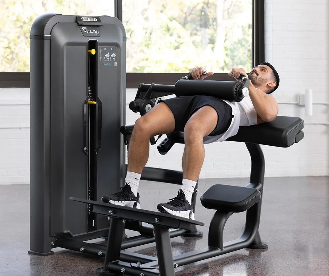 Front-angle view of a man an using the Keystone Glute Trainer in a gym.