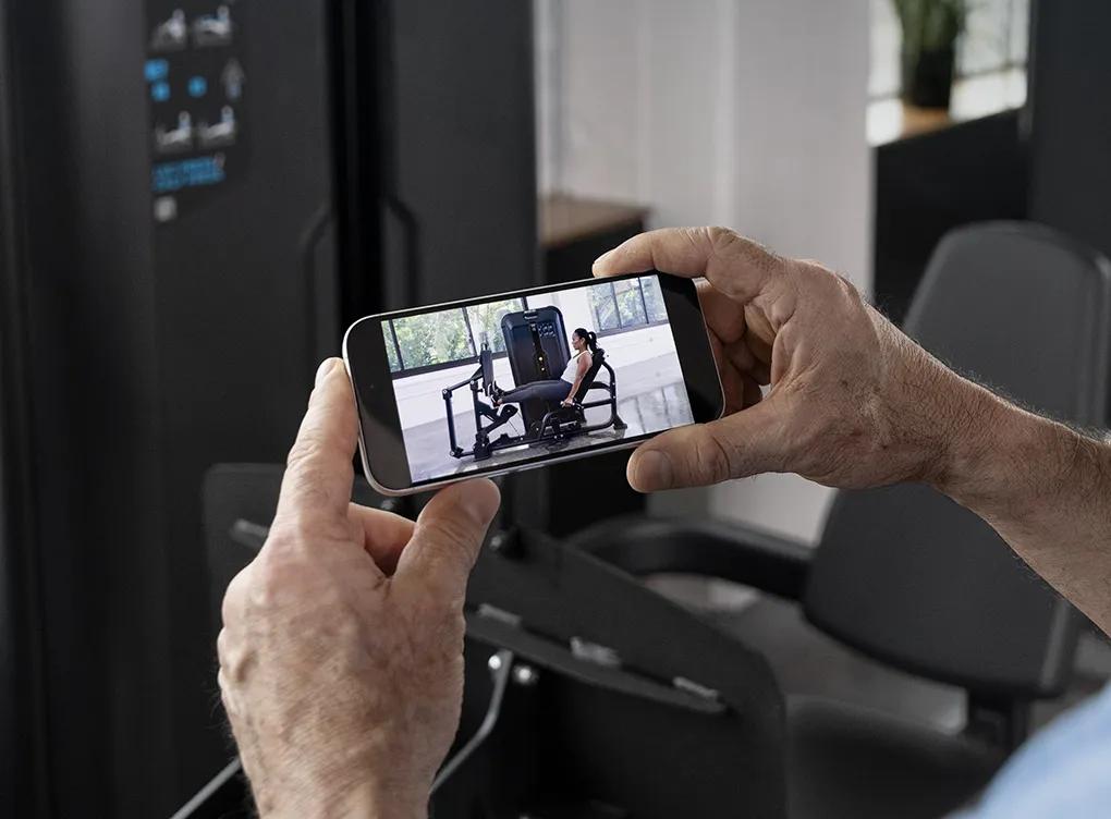 A person using there phone to watch a tutorial on how to use the equipment