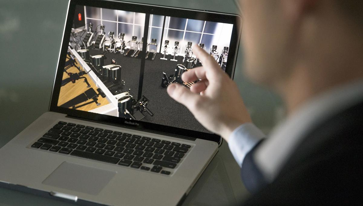 Person pointing to a laptop screen displaying a design mockup of a health club floor with cardio and strength equipment
