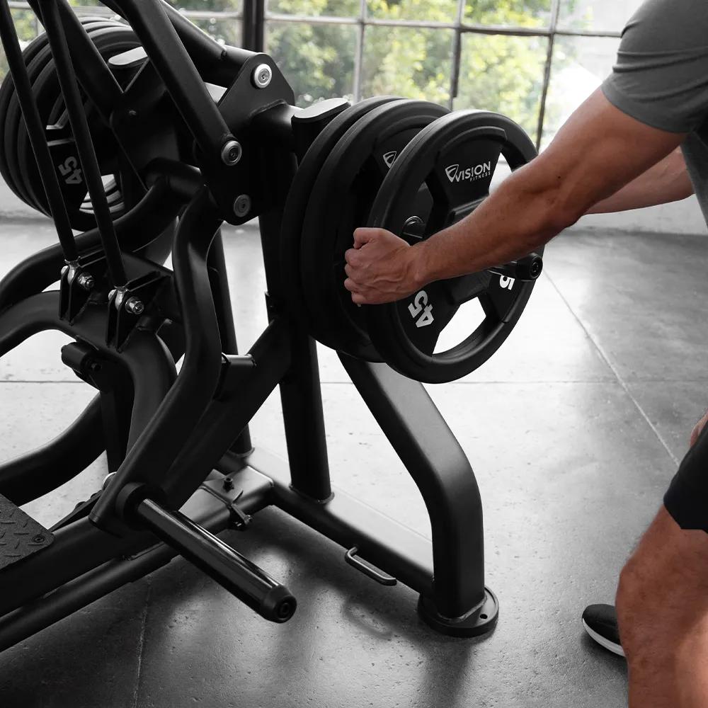 Person in workout clothes putting a weight plate on a Matte Black plate-loaded Leg Press's weight storage horn.