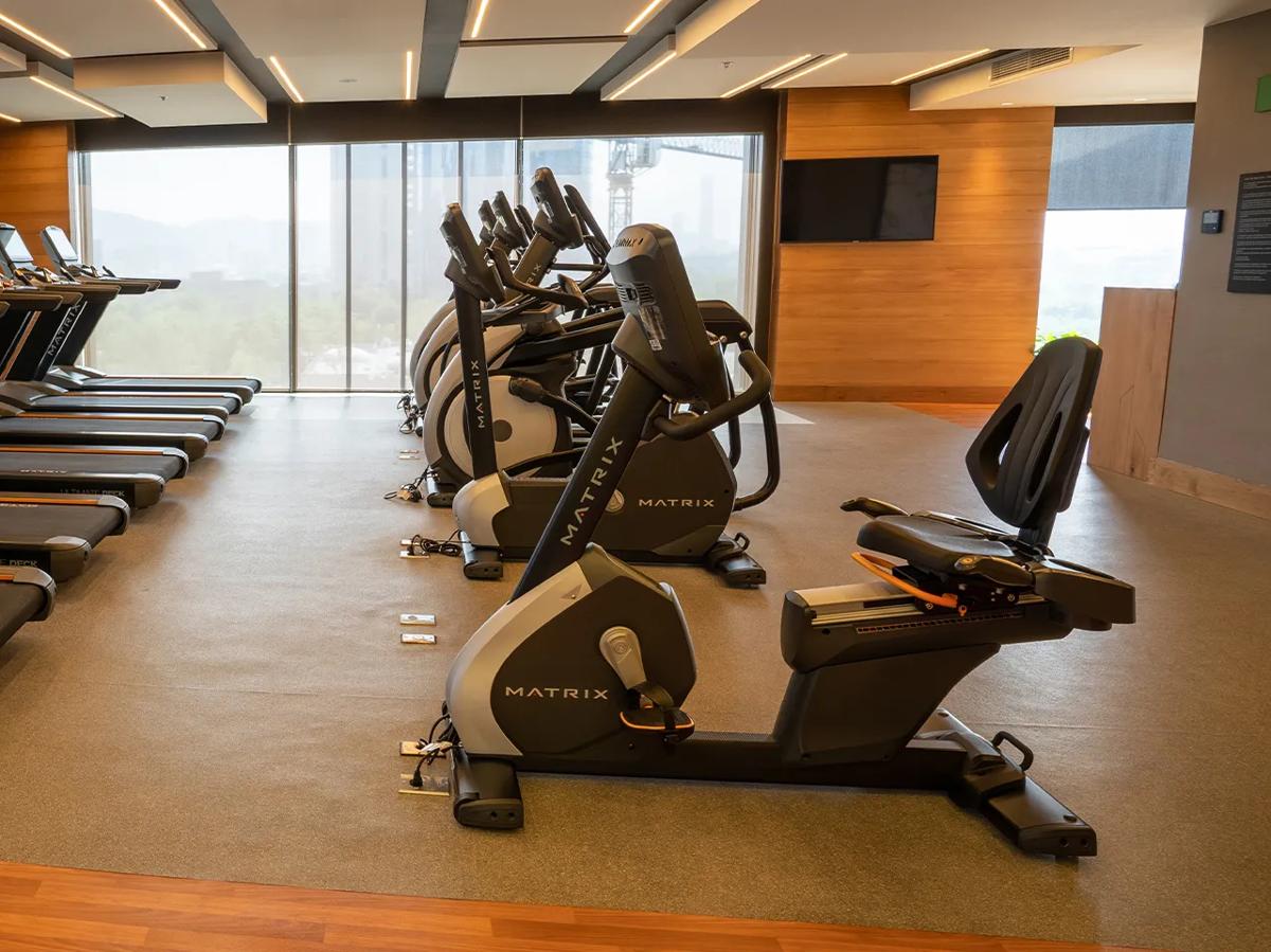 Salle de sport bien éclairée avec équipement de musculation Matrix et design élégant alliant béton et bois.