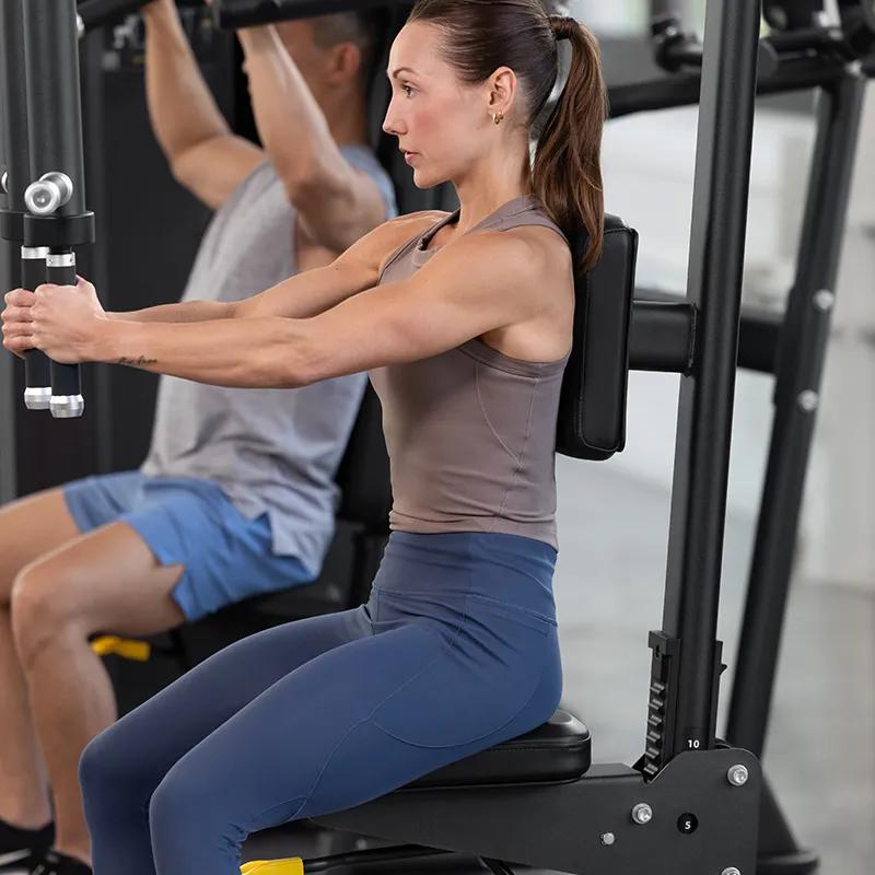 Person using the Vision Fitness Pec Fly/Rear Delt machine to perform a pec fly exercise, seated upright with arms pressing inward.