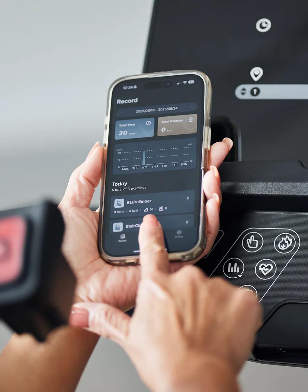 A Person using the Vision App on their phone along with the Vision console to track workouts