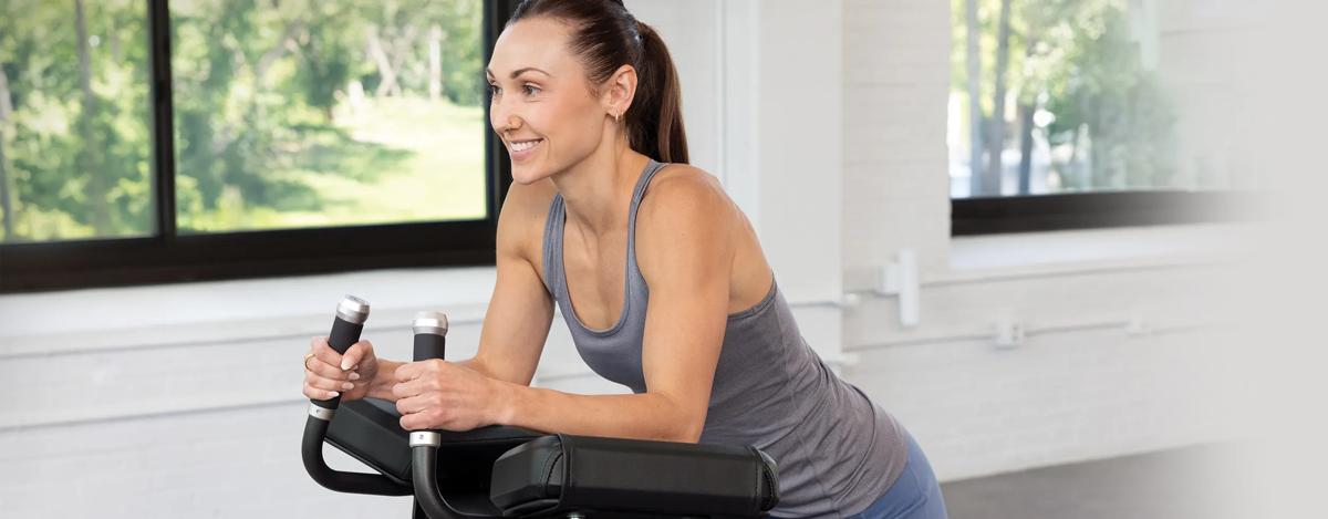 A person smiling while resting their arms on the top pad with both hands on the rubber hands.