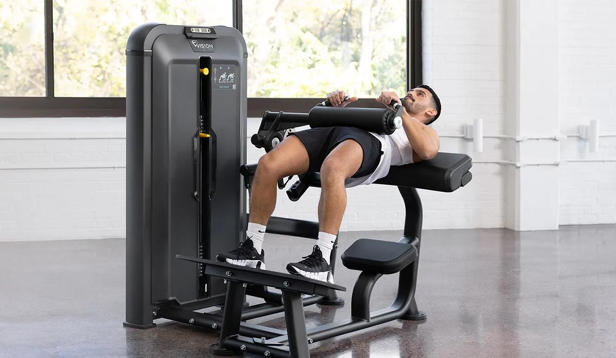 Front-angle view of a man an using the Keystone Glute Trainer in a gym.