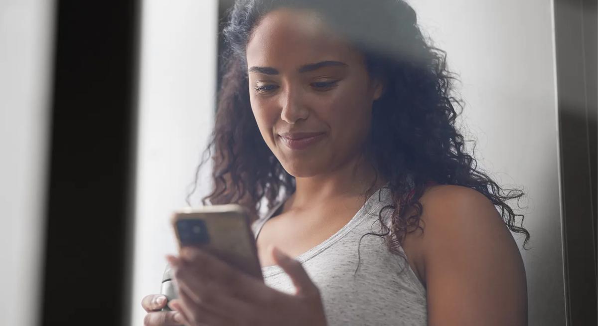 Una persona al cellulare con una bottiglia d'acqua nell'altra mano.