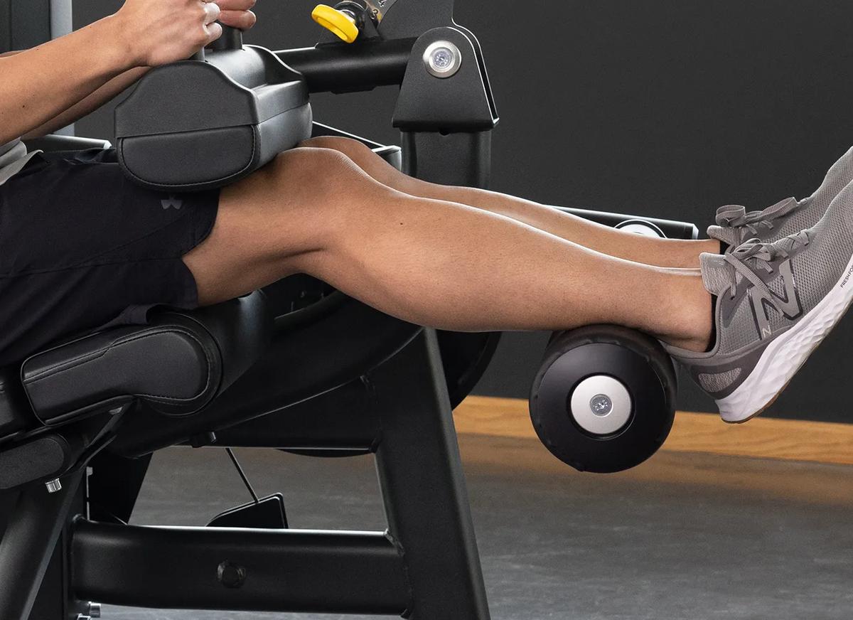 Close-up of a person using the Keystone Seated Leg Curl, highlighting the padded ankle roller.