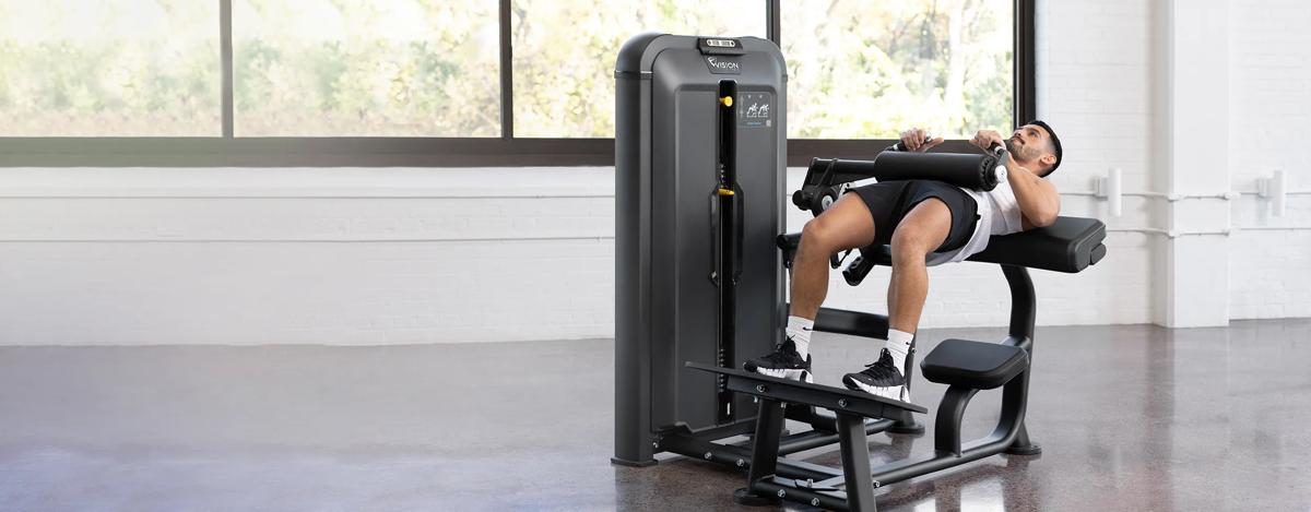 Front-angle view of a man an using the Keystone Glute Trainer in a gym.