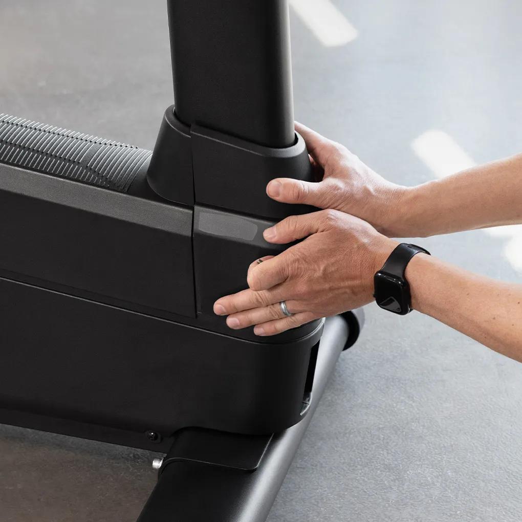 A person removing the Summit Upright Bike's case for maintenance.