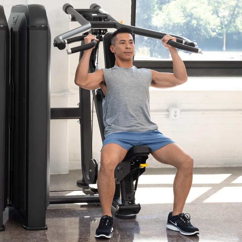 Twee mensen aan elk uiteinde van de barbell die gewichten laden in een lichte kamer met grote ramen.