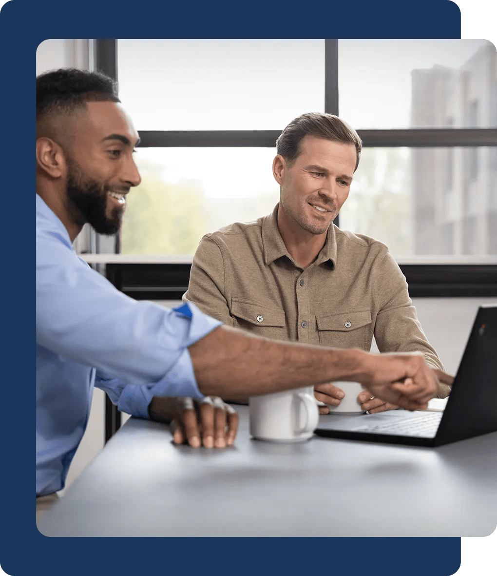 Two people working on a laptop together in an office setting