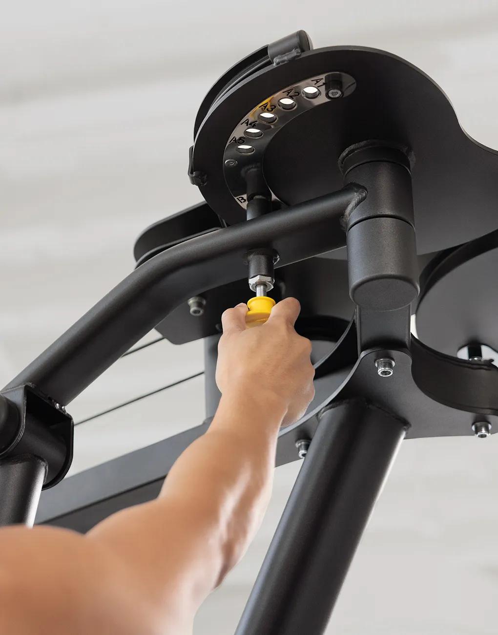Close-up of a person adjusting the arm position on the Vision Fitness Pec Fly/Rear Delt machine using the yellow selector pin.