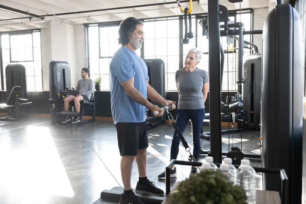 Two people chat while using Vision Fitnes Access Series strength equipment.