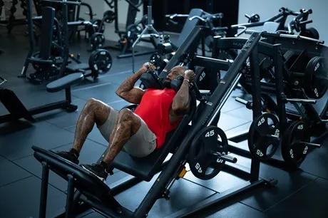 A person in workout clothes in a strength gym in the middle of doing a squat