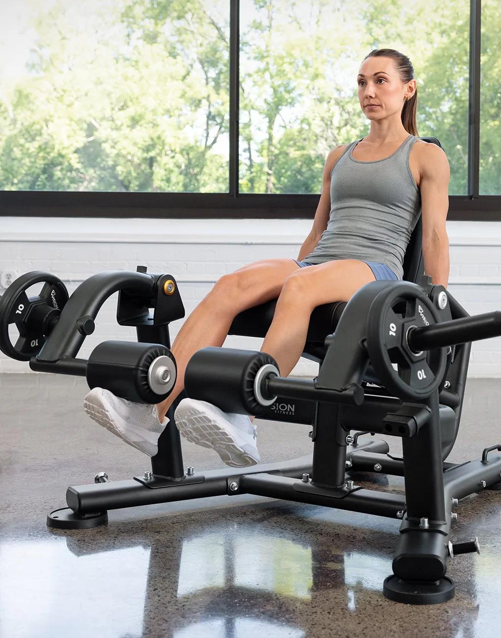 A person sitting on the Vision Leg Extension with both legs on the pads to begin the movement.
