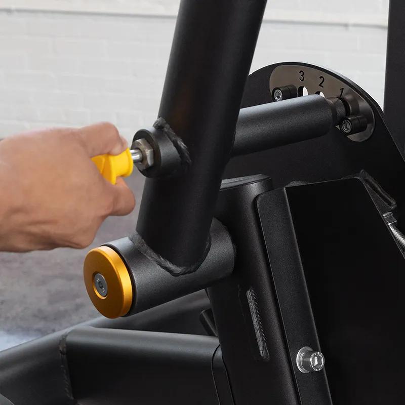 Close-up of a person adjusting the range of motion on the Vision Fitness Back Extension machine using the yellow selector pin.