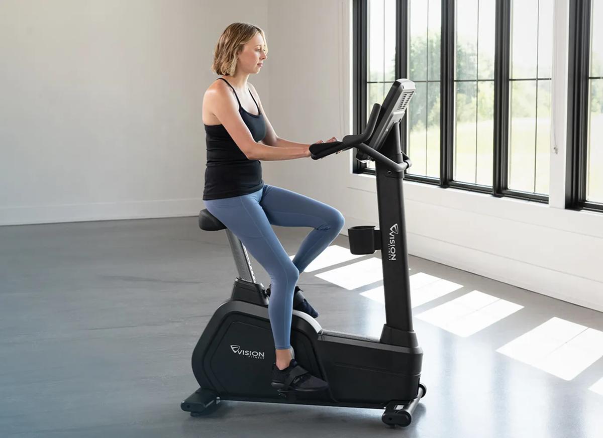 A person using the Summit Upright Bike in a large, open room.