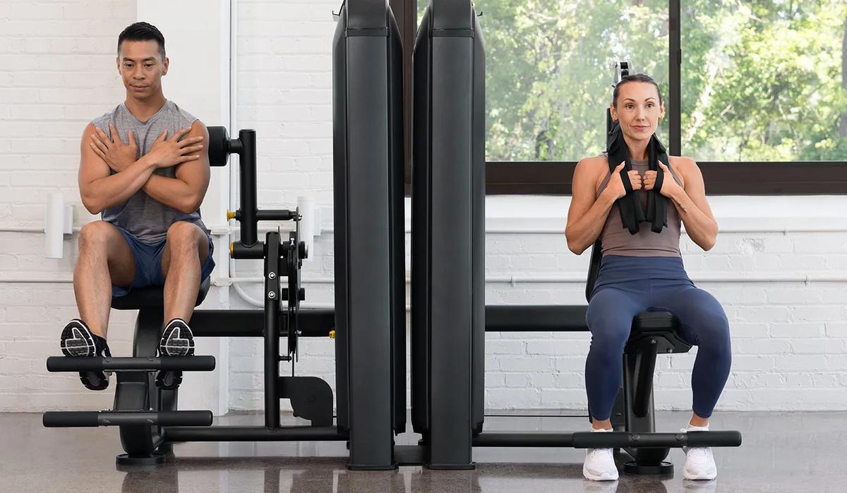 Person using the Vision Fitness Abdominal machine, performing a seated crunch with the cable-connected shoulder harness engaged.