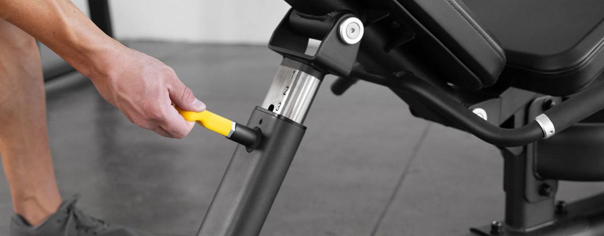 Person adjusting the seat position of a Matte Black plate-loaded Leg Press in a gym.