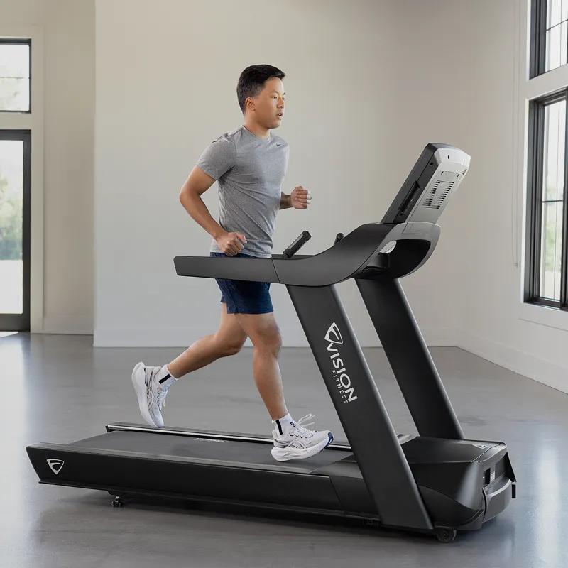 A person running on the Summit Treadmill in a large, brightly lit gym setting.