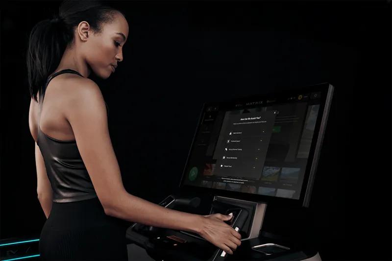 A person standing on a treadmill with their right hand on the controls