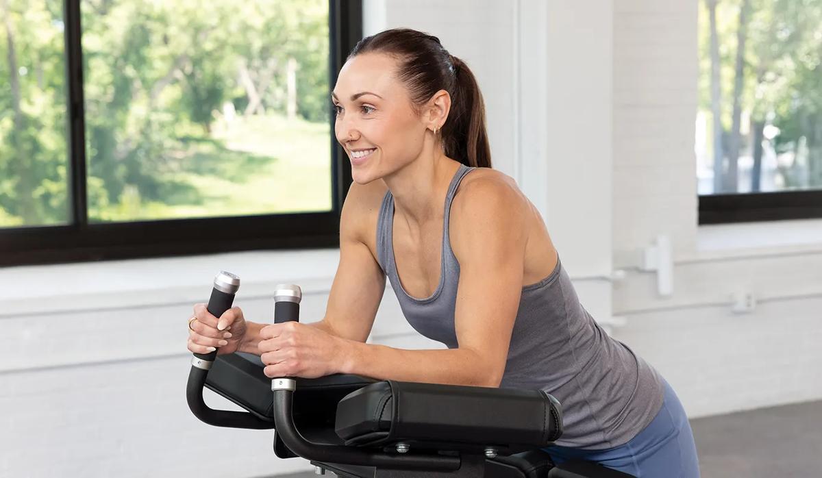A person smiling while resting their arms on the top pad with both hands on the rubber hands.