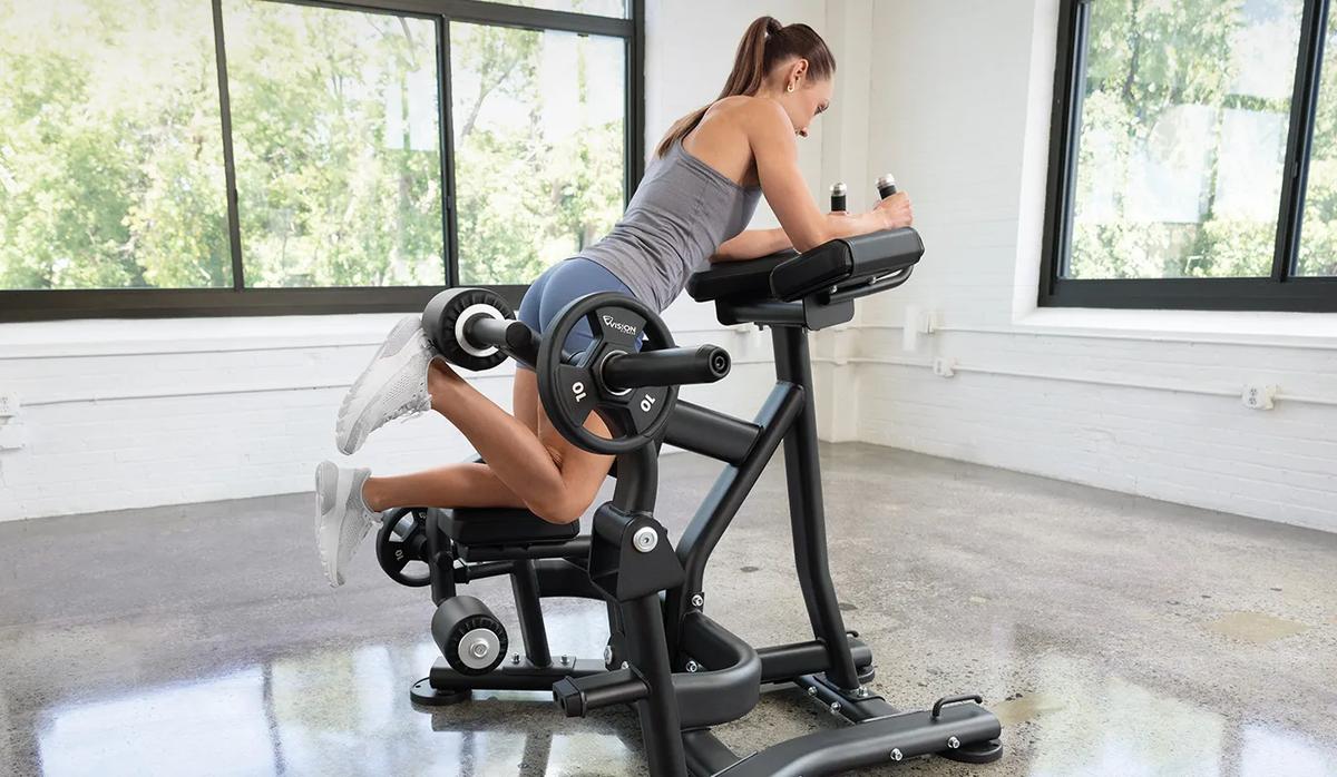 A person in blue shorts kneeling on the Vision Kneeling Leg Curl with their right leg bent with weights.