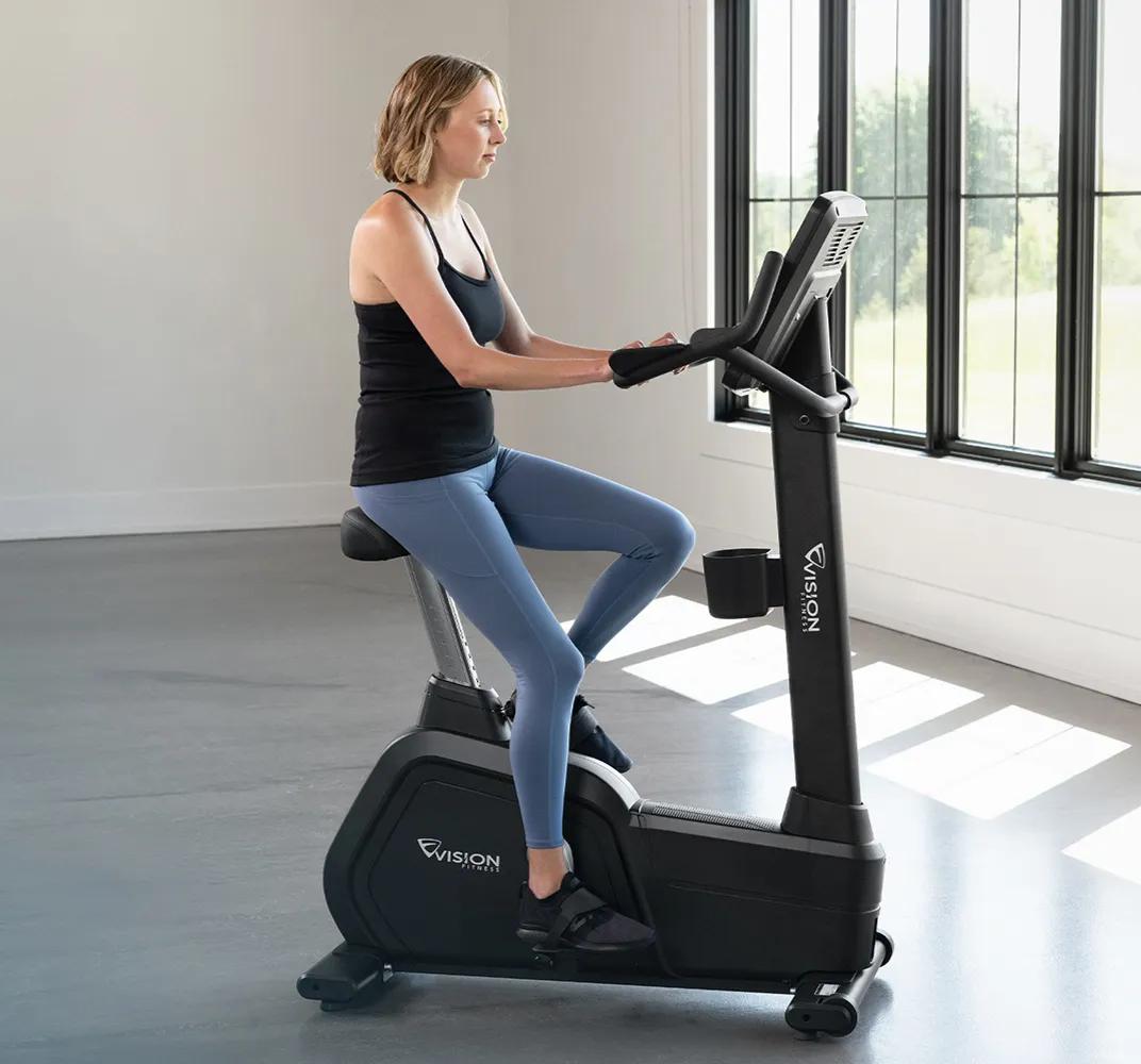 A person using the Summit Upright Bike in a large, open room.