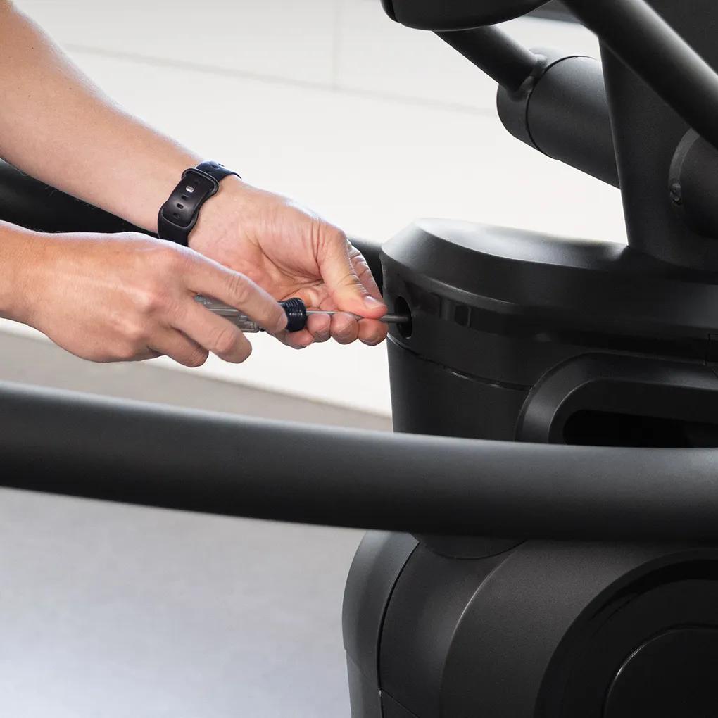 A person using a screwdriver to open the Summit Ascent Trainer for maintenance.