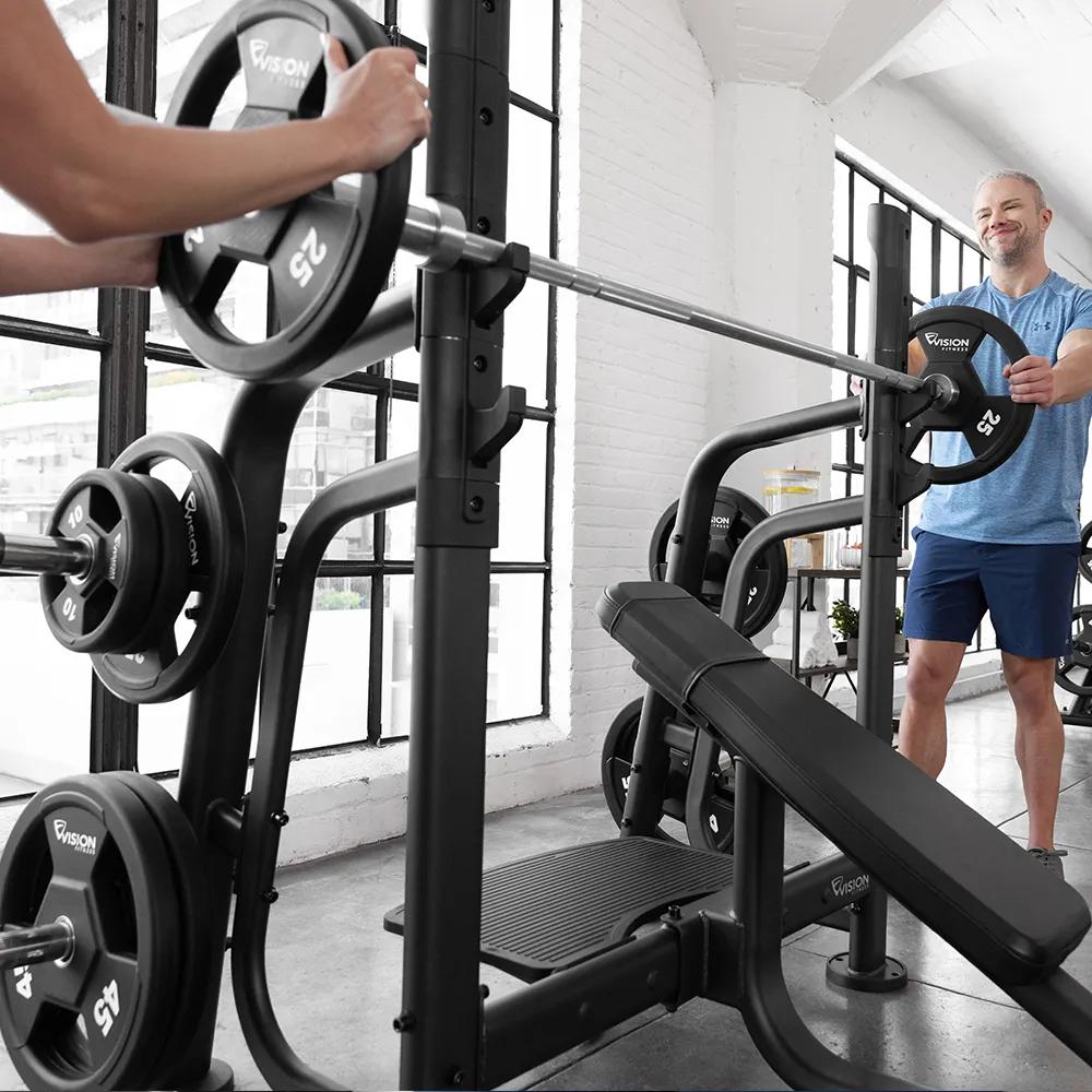 Person in workout clothes loading a weight plate onto a barbell on a Matte Black free weight Olympic Incline Bench.