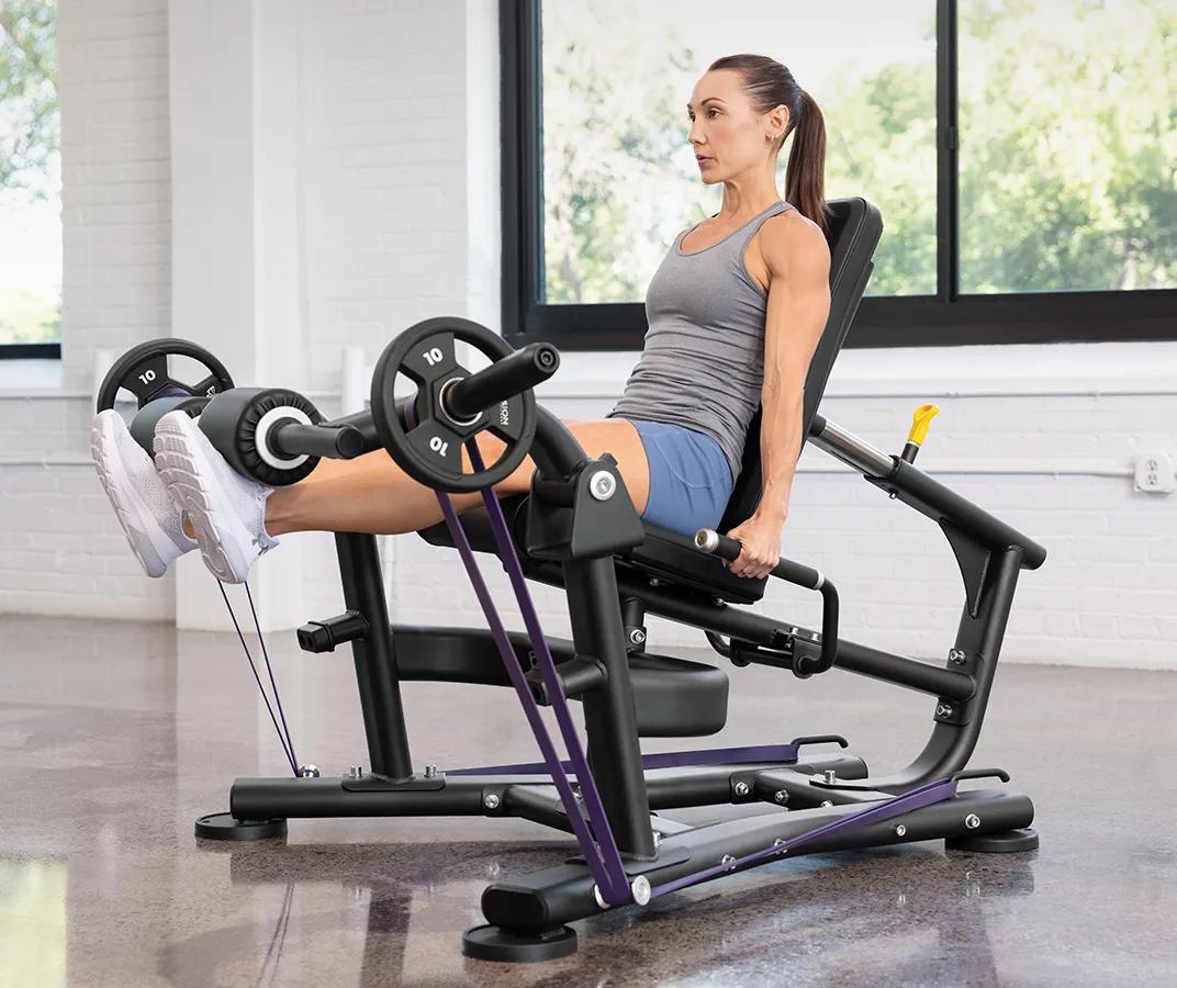 A person with their legs straight out with weights and resistant bands on the Vision Leg Extension.