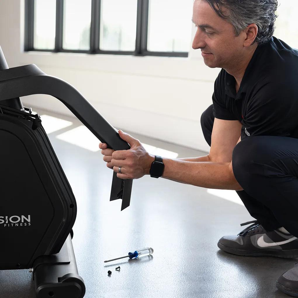 A person removing the protective cover from a Summit Recumbent Bike for maintenance.