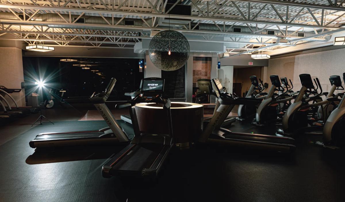 Row of Matrix Fitness treadmills with large digital screens, positioned in a modern gym.