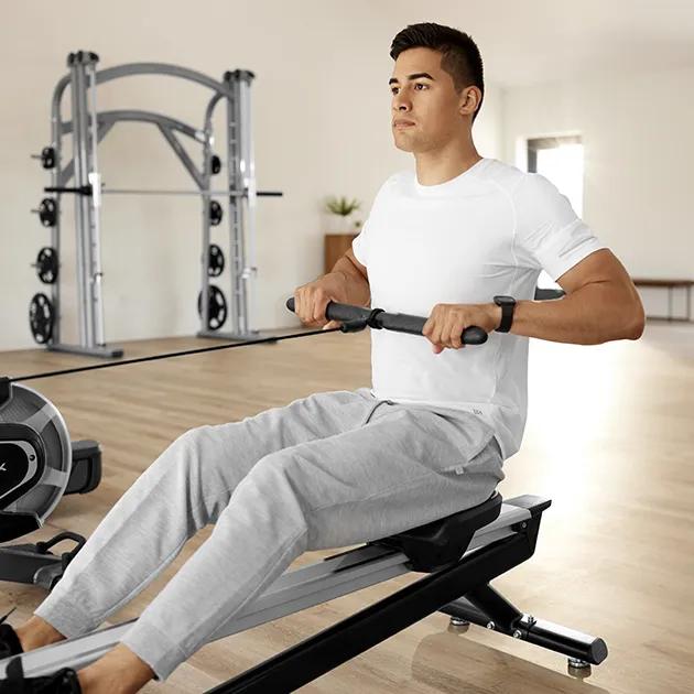 A man wearing a white shirt and gray sweats using a Matrix seated row machine.