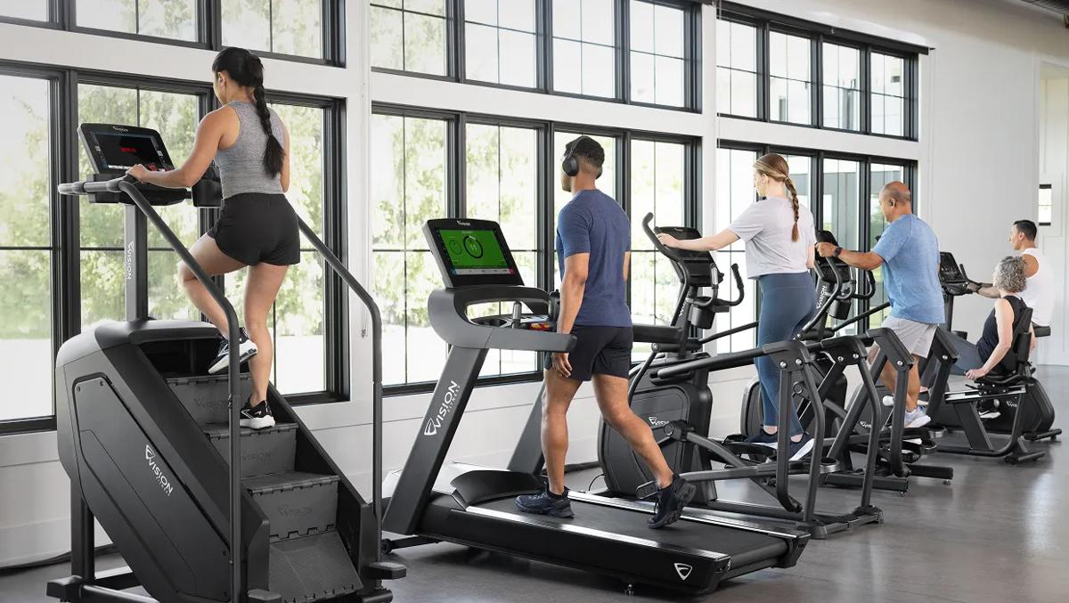 A lineup of Vision cardio equipment being used in a gym 