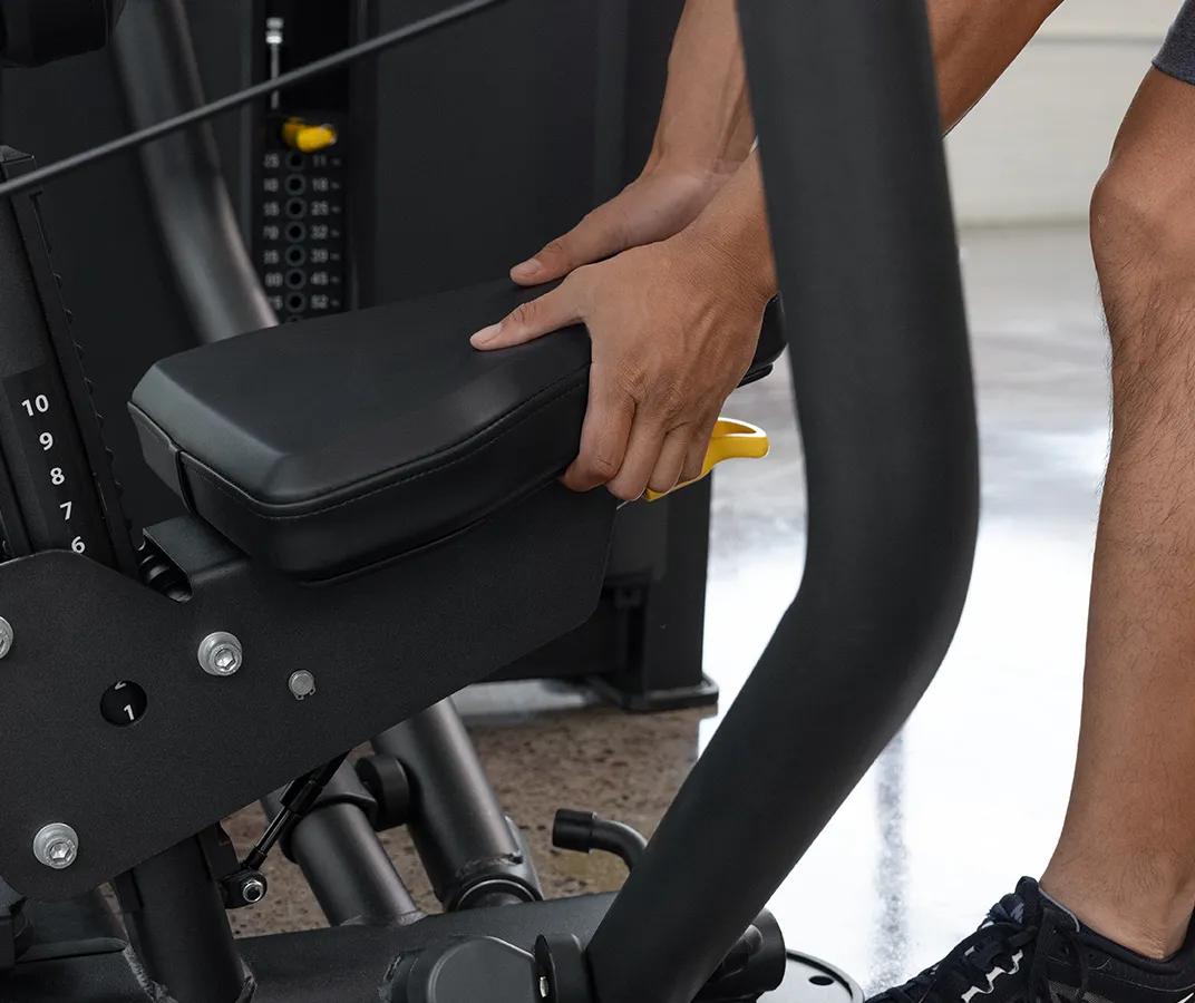 Close-up of a person adjusting the seat height on the Vision Fitness Chest Press machine in Matte Black using the yellow lever beneath the padded seat.