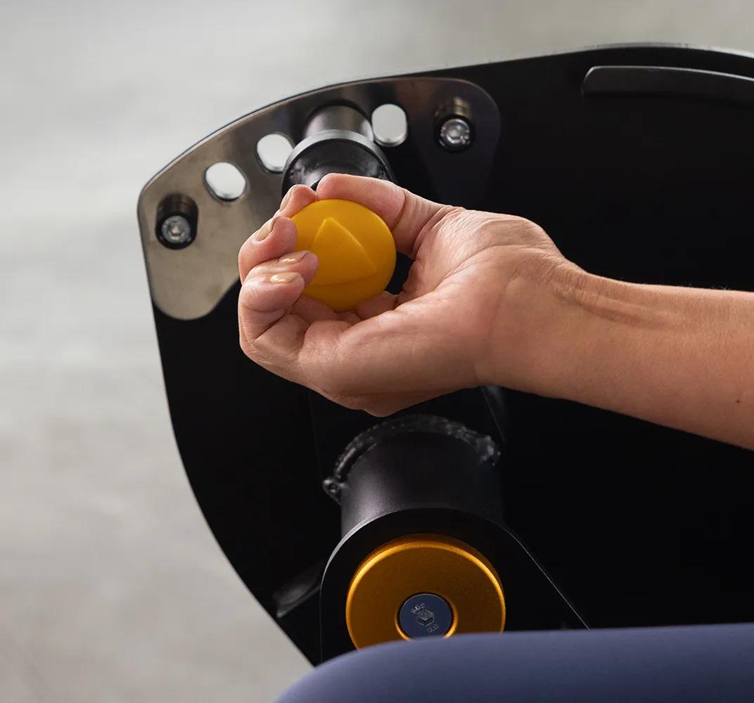 Close-up of a person using the Keystone Leg Extension adjustment arm with yellow pop-pin and pivot hardware.