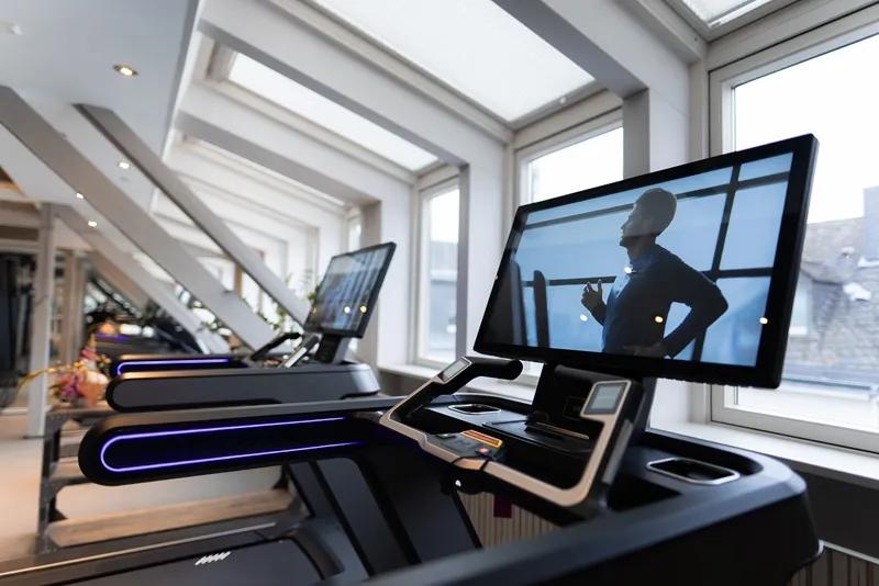 A large console screen with a person running on it in front of bright white windows