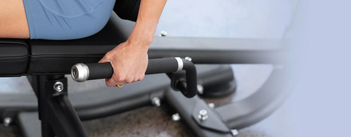 A person's left hand on the rubber handles on the side of the Vision Leg Extension.