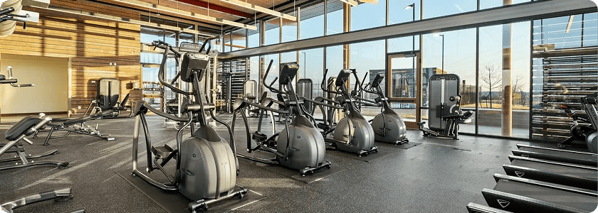 A large gym with floor to ceiling windows with cardio equipment throughout