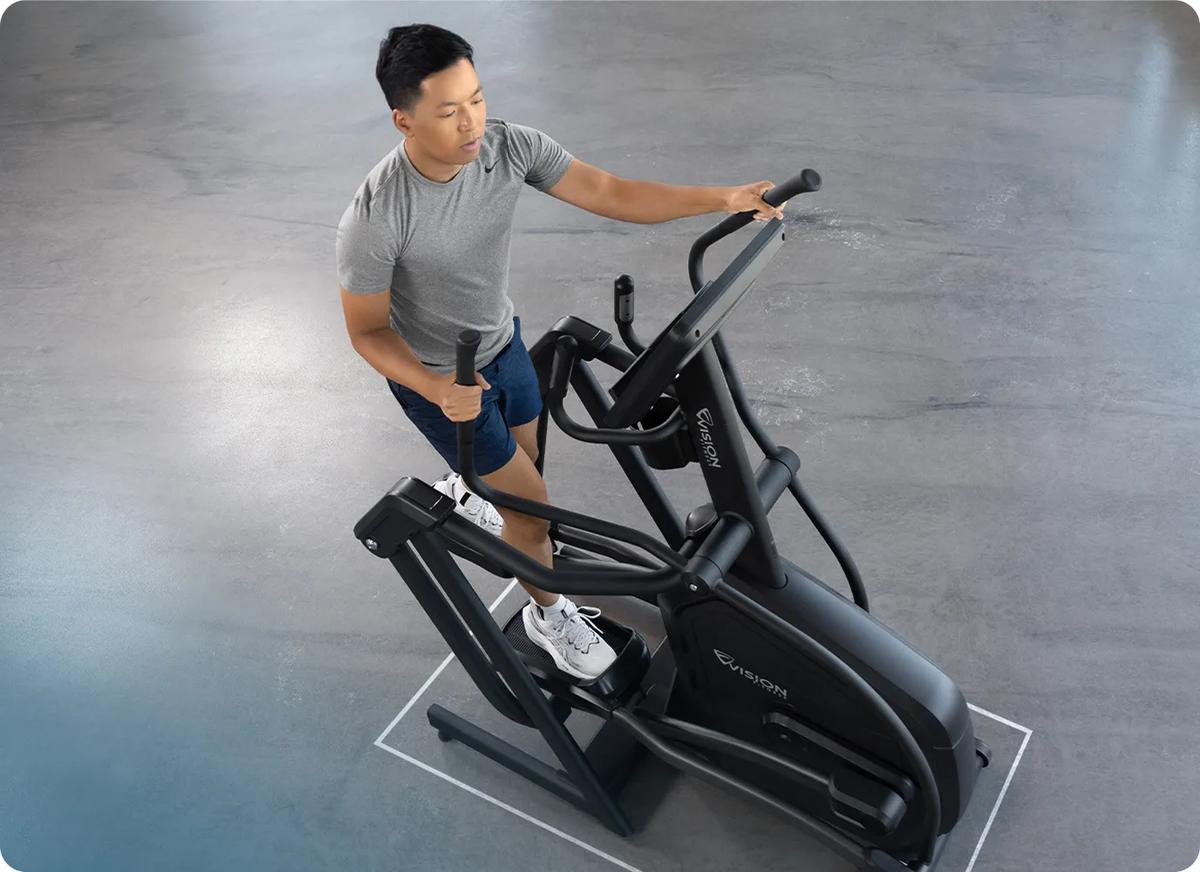 Full view of a person using the Summit Suspension Elliptical in a gym setting.