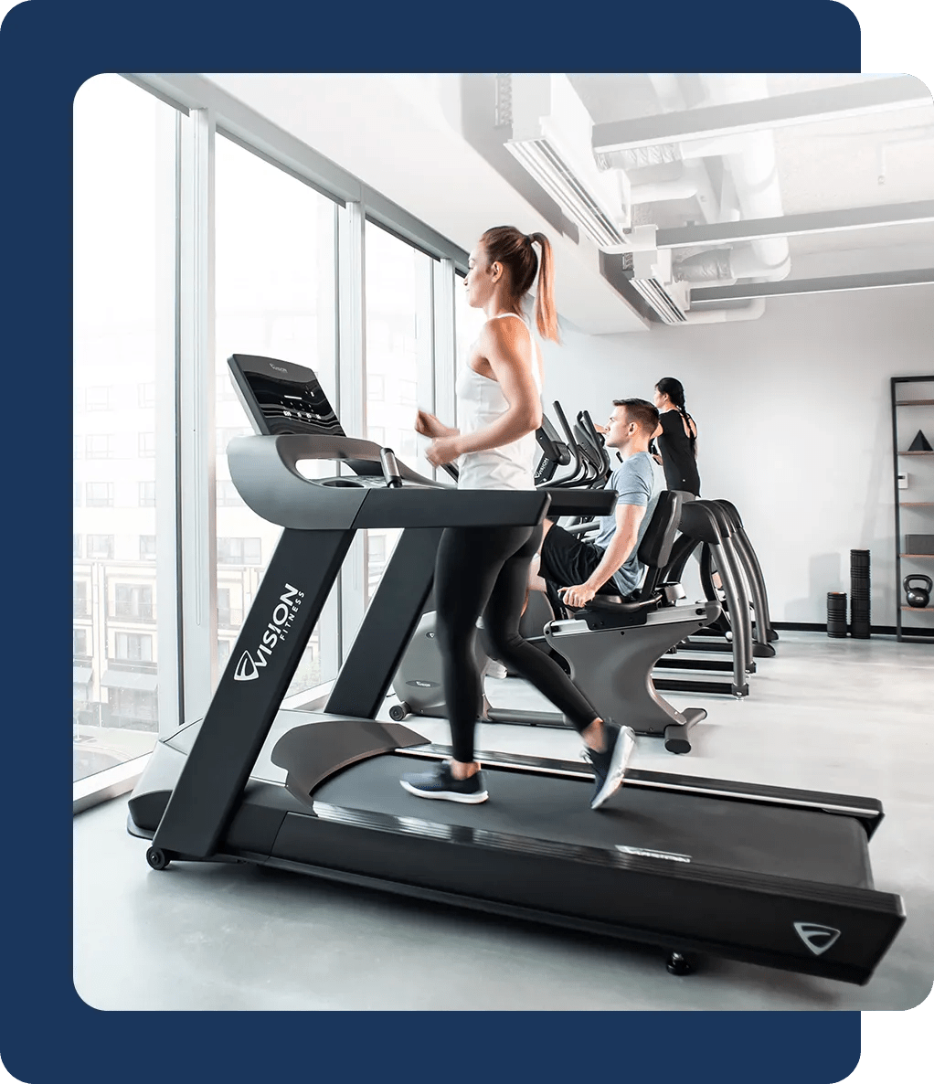 A group of people working out on Vision cardio equipment in a bright room with large windows.