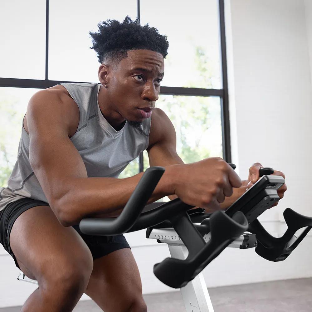 A person in a gray workout top with their arms rest on the handbars, comfortability. 
