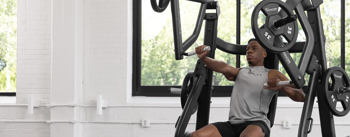A person with weights on the Vision Vertical Chest Press, pressing out with the right arm.