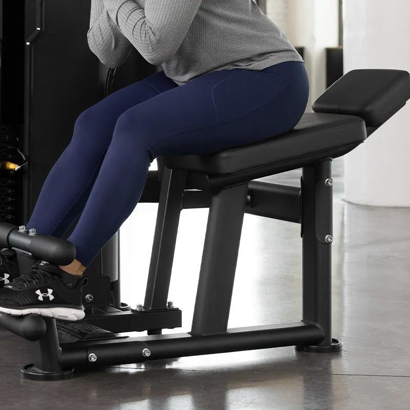 Side view of the Ab / Low Back machine showing adjustable thigh hold-down roller, seat pad, back pad, horizontal handles, and enclosed weight stack.