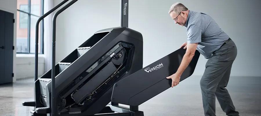 Maintenance man fixing the Vision Summit Stairclimber.